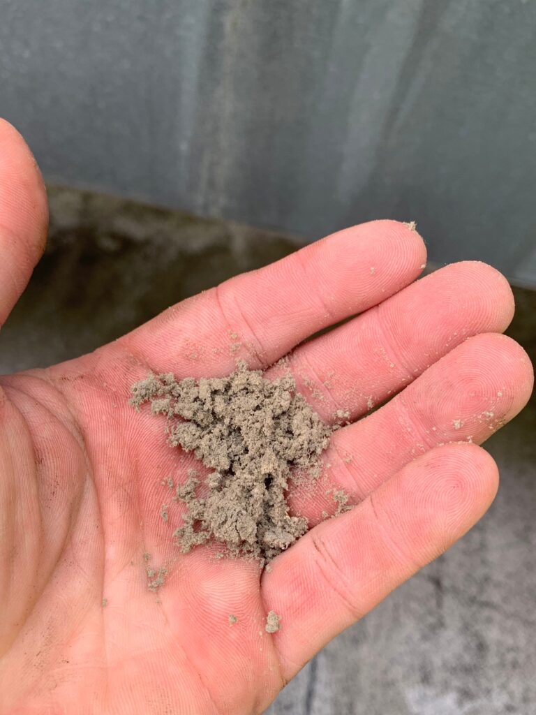 Hand holding dirty air duct lint and debris, demonstrating the need for professional duct cleaning services.