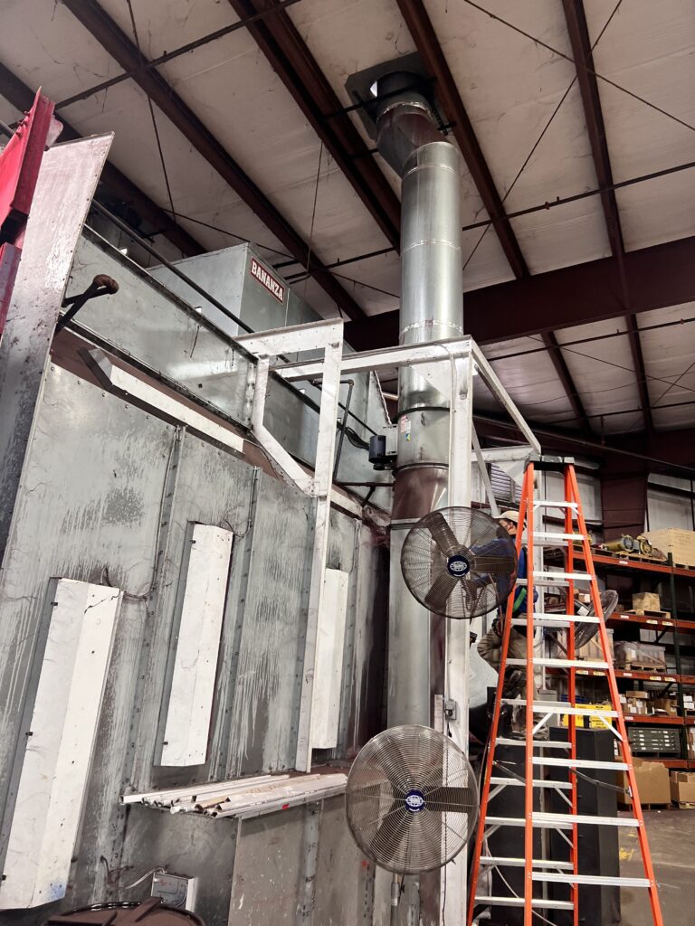Industrial ventilation system with metal ducts, ladder, and fans in a warehouse for air duct cleaning services