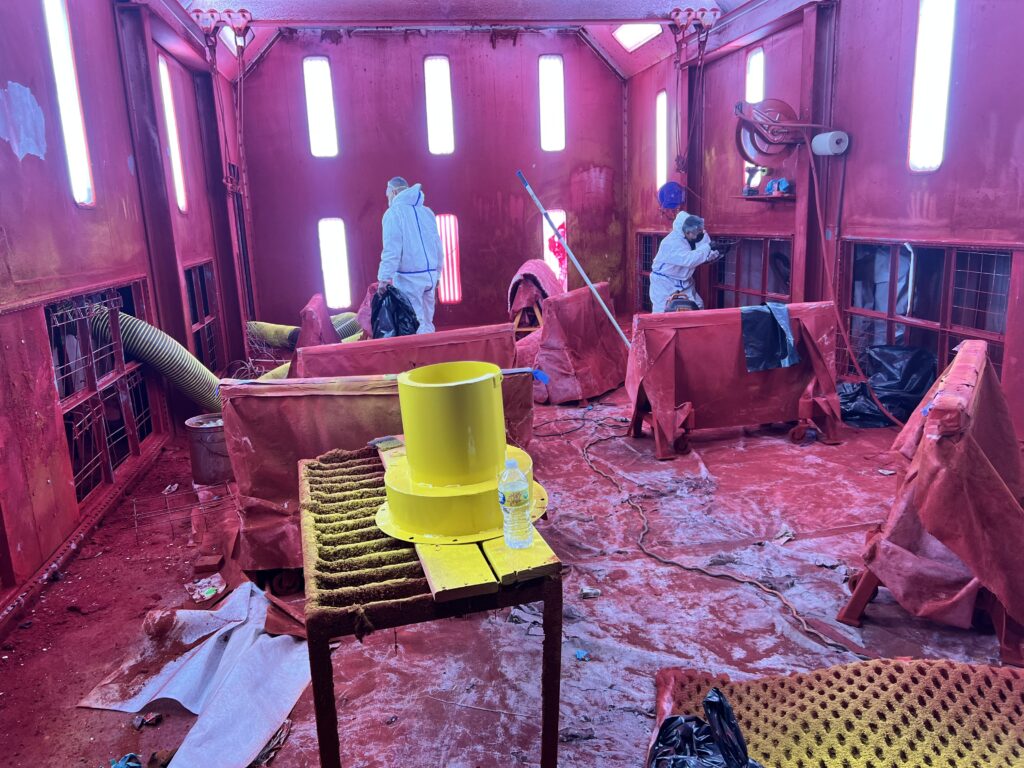 Workers in protective suits clean a home's ductwork, using industrial vacuums and brushes to remove debris