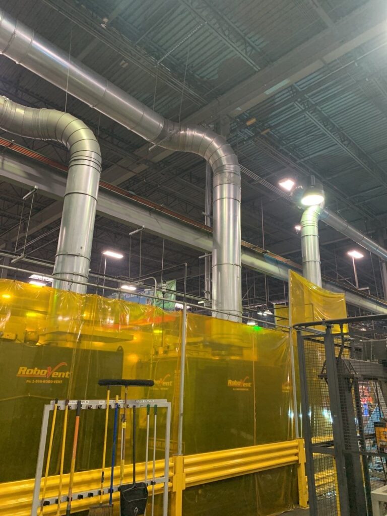 Industrial ventilation system with yellow Robovent air filtration units installed in a warehouse ceiling