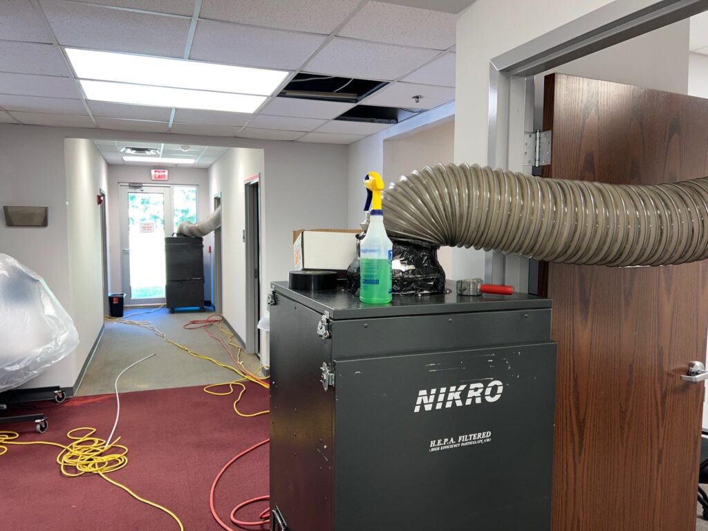 Air duct cleaning equipment in a commercial space, featuring a Nikro HEPA filtered vacuum system.