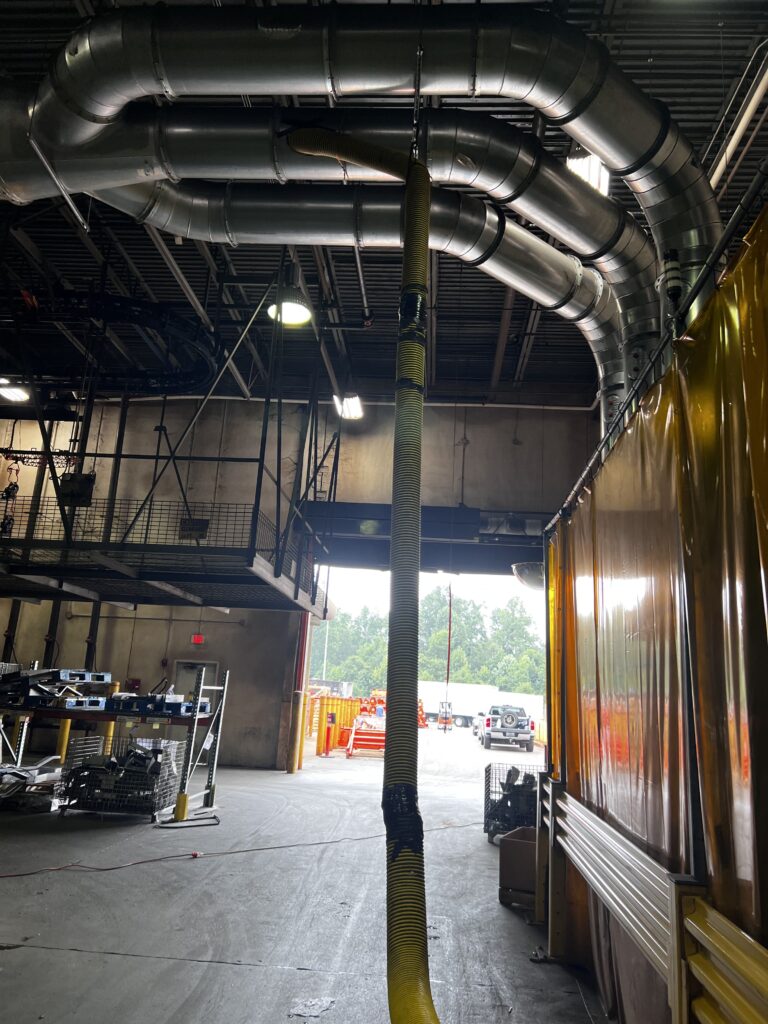 Industrial garage interior with exposed HVAC ductwork, tools, equipment for air duct cleaning services