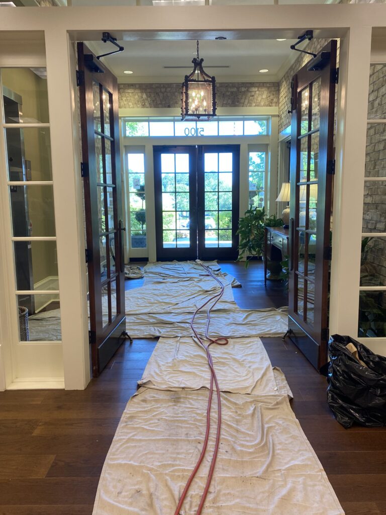 Drop cloths cover floor in entryway with double French doors for air duct cleaning service protection