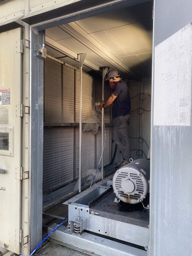 Technician cleans industrial air ducts for improved HVAC efficiency and indoor air quality.