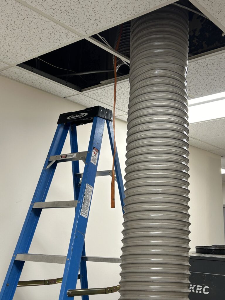 Commercial air duct cleaning service - technician's ladder and industrial flexible ducting hose