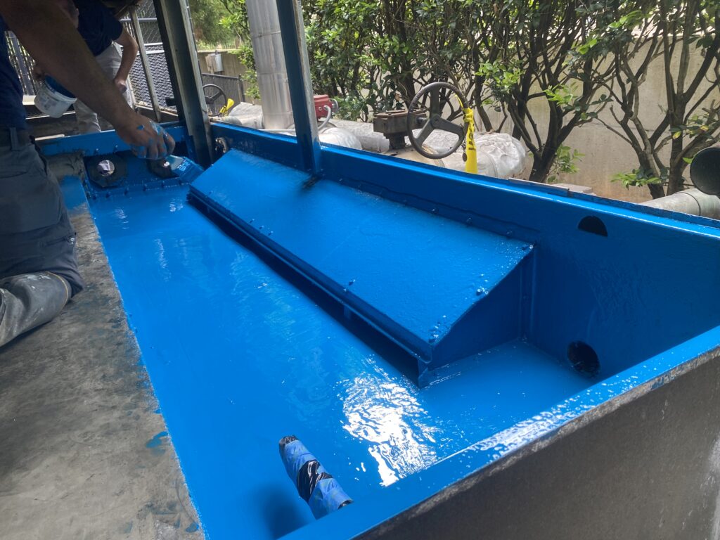 Technician applying sealant to bright blue HVAC air ducts, ensuring efficient residential ventilation.