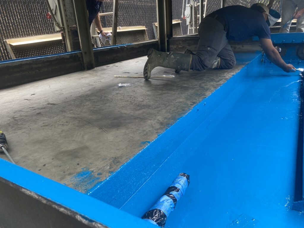 Workers cleaning blue-painted commercial or industrial HVAC air ducts to ensure indoor air quality.