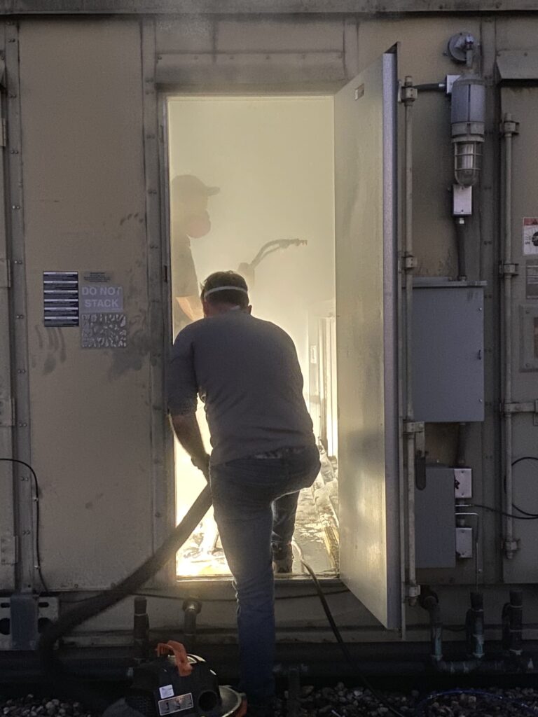 Technician inspecting HVAC system in confined space, ensuring clean air ducts for commercial clients.