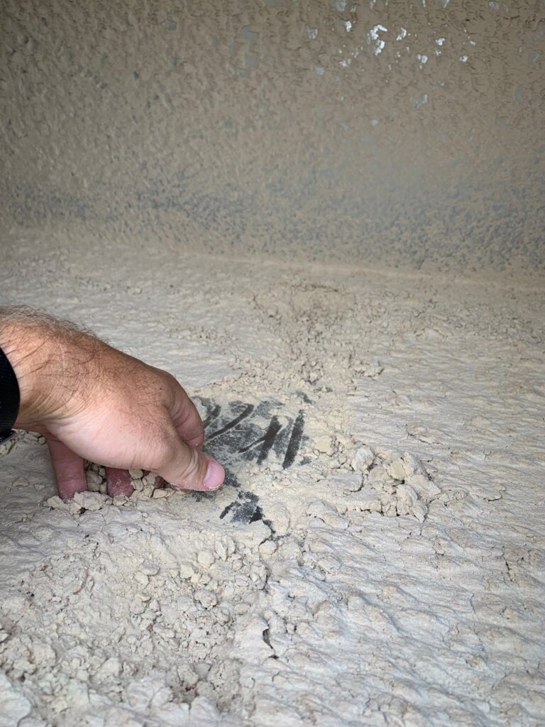 Hand pointing to dirty, debris-filled air duct vent, illustrating the need for professional cleaning services.
