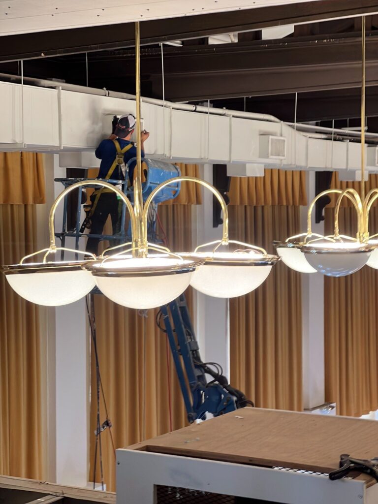 Commercial air duct cleaning service, technician on lift, examining ductwork with bright lights
