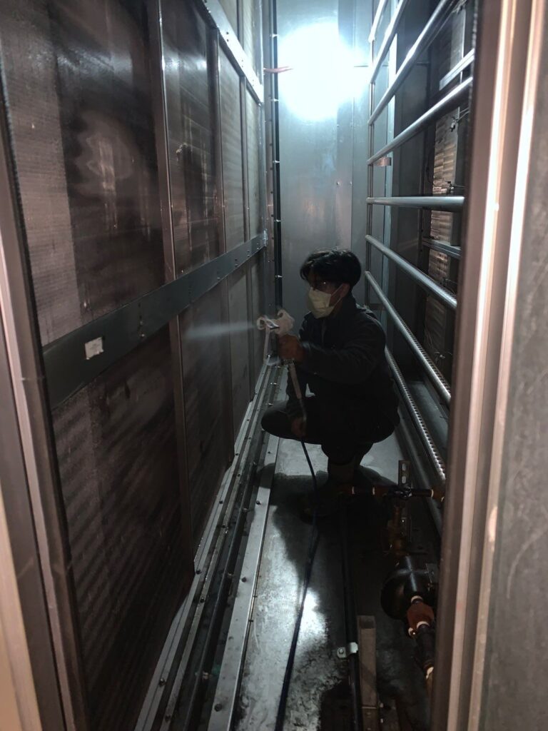 Technician inspecting ducts in narrow utility corridor, ensuring thorough commercial air duct cleaning.
